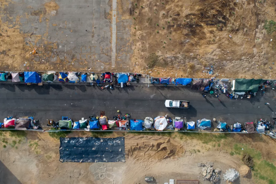 Aerial bird's eye view of unhoused encampment along roadside in Sacramento, California.